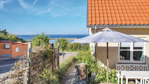 Ein Küstenanwesen mit Ziegeldach, einem Garten mit einer Pergola und Meerblick.