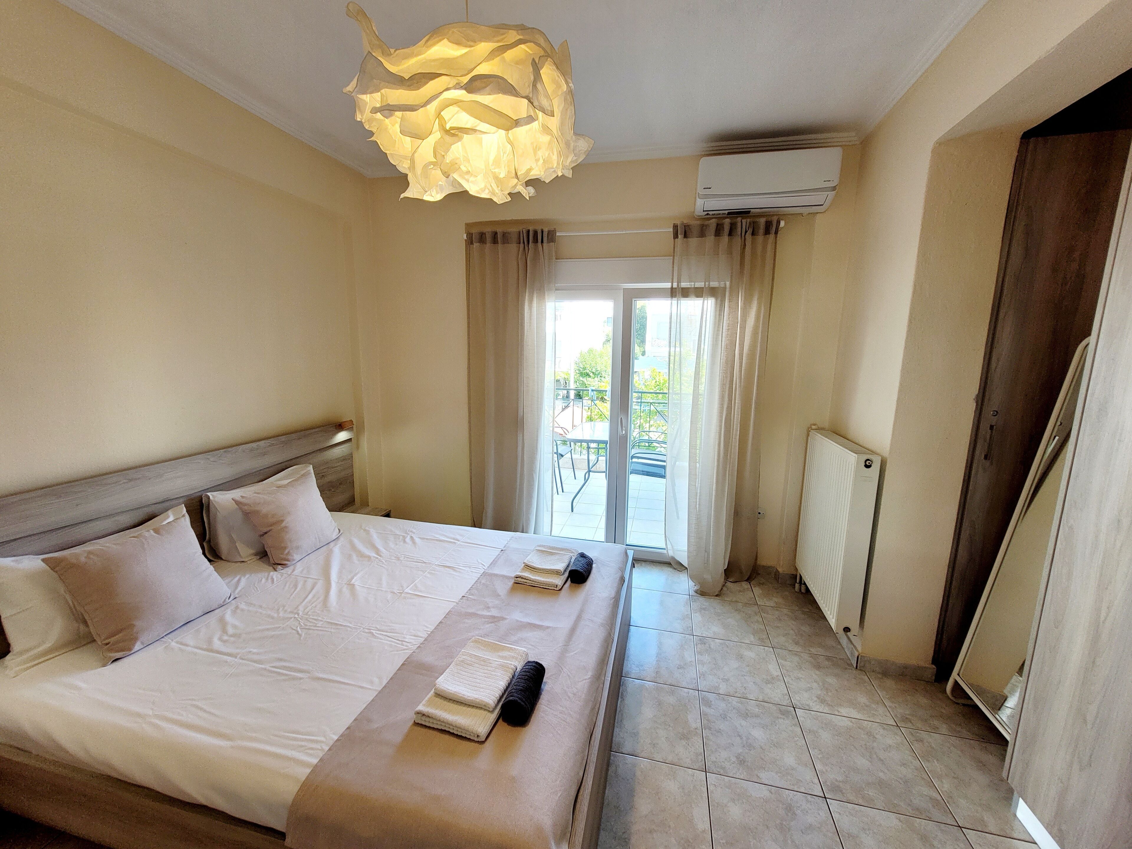 Een hotelkamer met een bed, een plafondlamp, een airconditioning en uitzicht op het balkon.