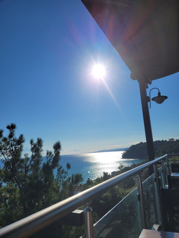 Un balcon avec vue sur la mer et une côte lointaine.