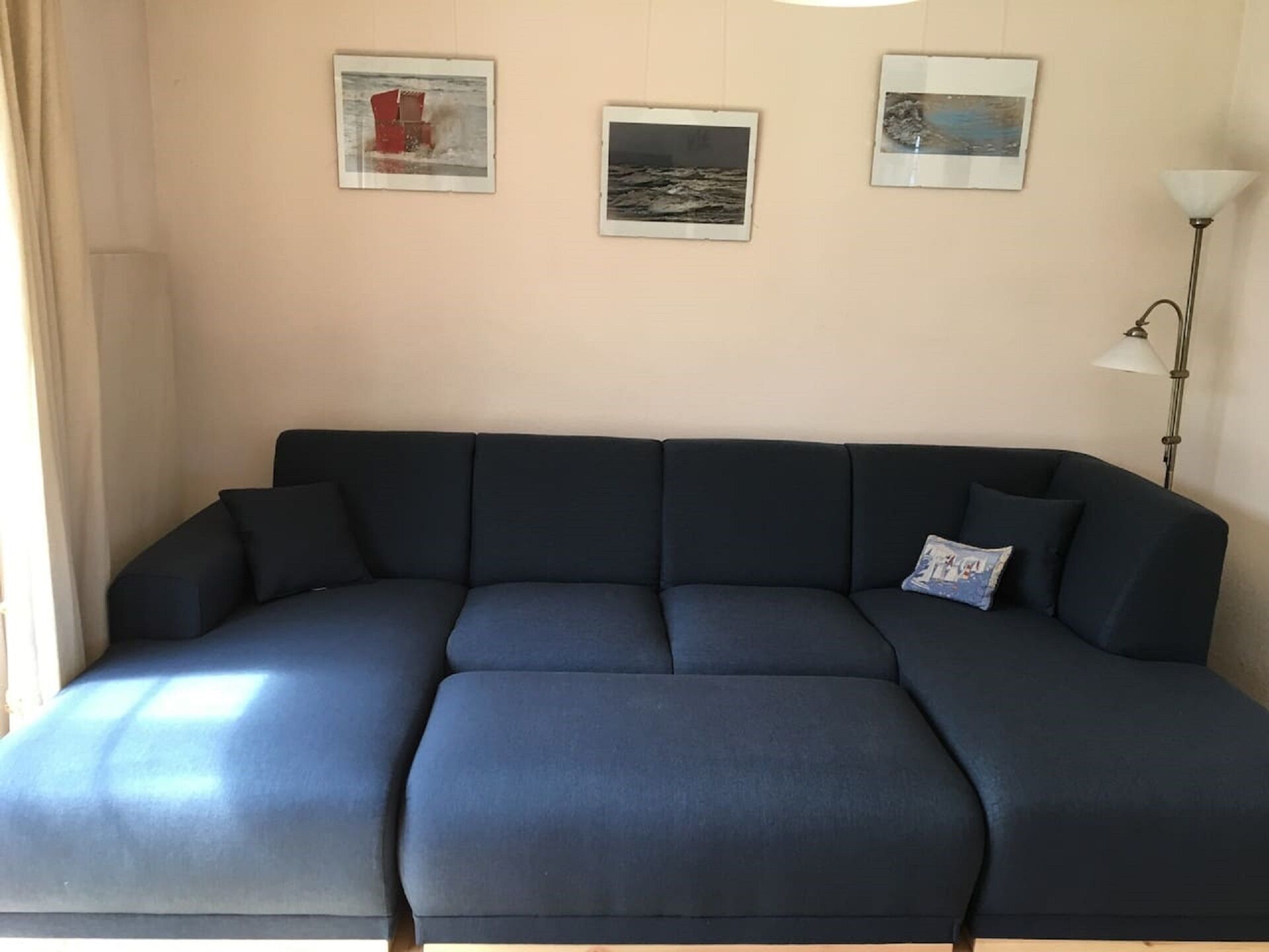 Un canapé bleu foncé dans une pièce où sont accrochées trois images encadrées au mur.