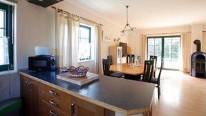 A kitchen with a microwave, wooden cabinets, and a dining area with a table and chairs. - The TROLLHUS is located in a small street on the edge of the Darss primeval forest (Born am Darß)