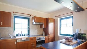 A kitchen with wooden cabinets, a stove, and a window. - The TROLLHUS is located in a small street on the edge of the Darss primeval forest (Born am Darß)