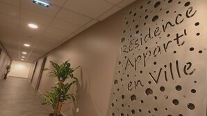 A hallway with a wall featuring the text "Résidence Appart en Ville" and potted plants. - Residence Appart'en Ville - studio 2 people (Saint-Flour)