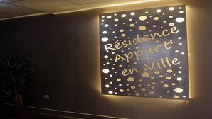 Eine an der Wand befestigte Leuchtreklame mit der Aufschrift 'Résidence Appart en Ville'.