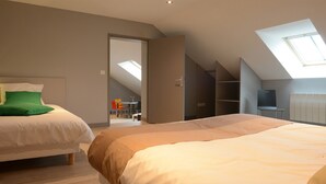 Une chambre avec deux lits, une lucarne et une vue sur un coin repas.