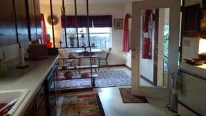 A kitchen with a dining area, a window with curtains, and a door leading outside. - Comfy Safe Quiet Haven, Dog Friendly!  2 Miles to Downtown or to Vilano Beach (St. Augustine)