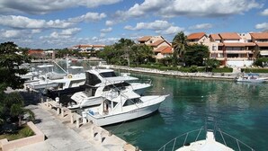 A marina with several yachts docked, surrounded by residential buildings and palm trees. - Quinta Del Sol, 3 Bedroom Beachfront Condo In Puerto Aventuras, Riviera Maya (puerto aventuras)
