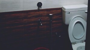 A bathroom with a toilet, a shower, and a wooden vanity. - Noise free home stay (Eranakulam)