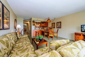 A living room with a sofa, a coffee table, and a dining area with chairs and a table.