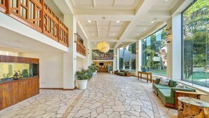 Eine geräumige Lobby mit Steinboden, einer Holzeinschneide und einer grünen Couch, große Fenster mit Blick ins Freie.
