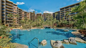 Ein Hotel mit mehreren Balkonen, einem Pool mit Felsen und Palmen.