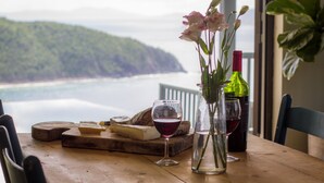A wooden table with a cheese board, wine glasses, and a vase with flowers. - Stylish, Secluded Villa with Pool, Hot tub and Stunning Views (Mount Healthy)