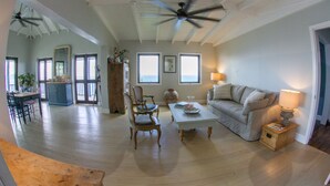 A spacious living room with a high ceiling, a ceiling fan, a dining area with a table and chairs, a sofa, and a lamp. - Stylish, Secluded Villa with Pool, Hot tub and Stunning Views (Mount Healthy)