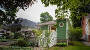 A green house with a small porch and a window. - The Lily Pad - quaint home in Old Town NOTL, steps from the lake! (Niagara-on-the-Lake)