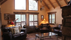 A cozy living room with leather sofas, a glass coffee table, and a fireplace. - Privacy & Location! One acre & 2min from town. Central AC. Covered patio. (Ruidoso)