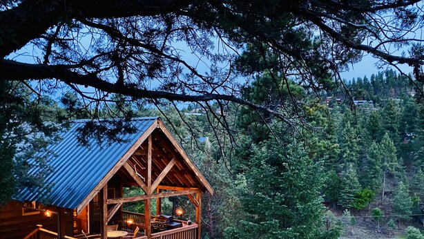 A wooden cabin with a balcony, surrounded by trees and a view of a lake. - Privacy & Location! One acre & 2min from town. Central AC. Covered patio. (Ruidoso)