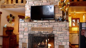 A stone fireplace with a mounted television and a deer head above it. - Privacy & Location! One acre & 2min from town. Central AC. Covered patio. (Ruidoso)
