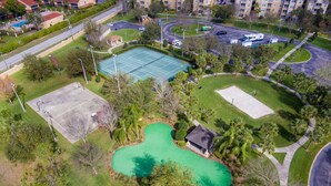 An aerial view of a golf course with a tennis court, a swimming pool, and a clubhouse.