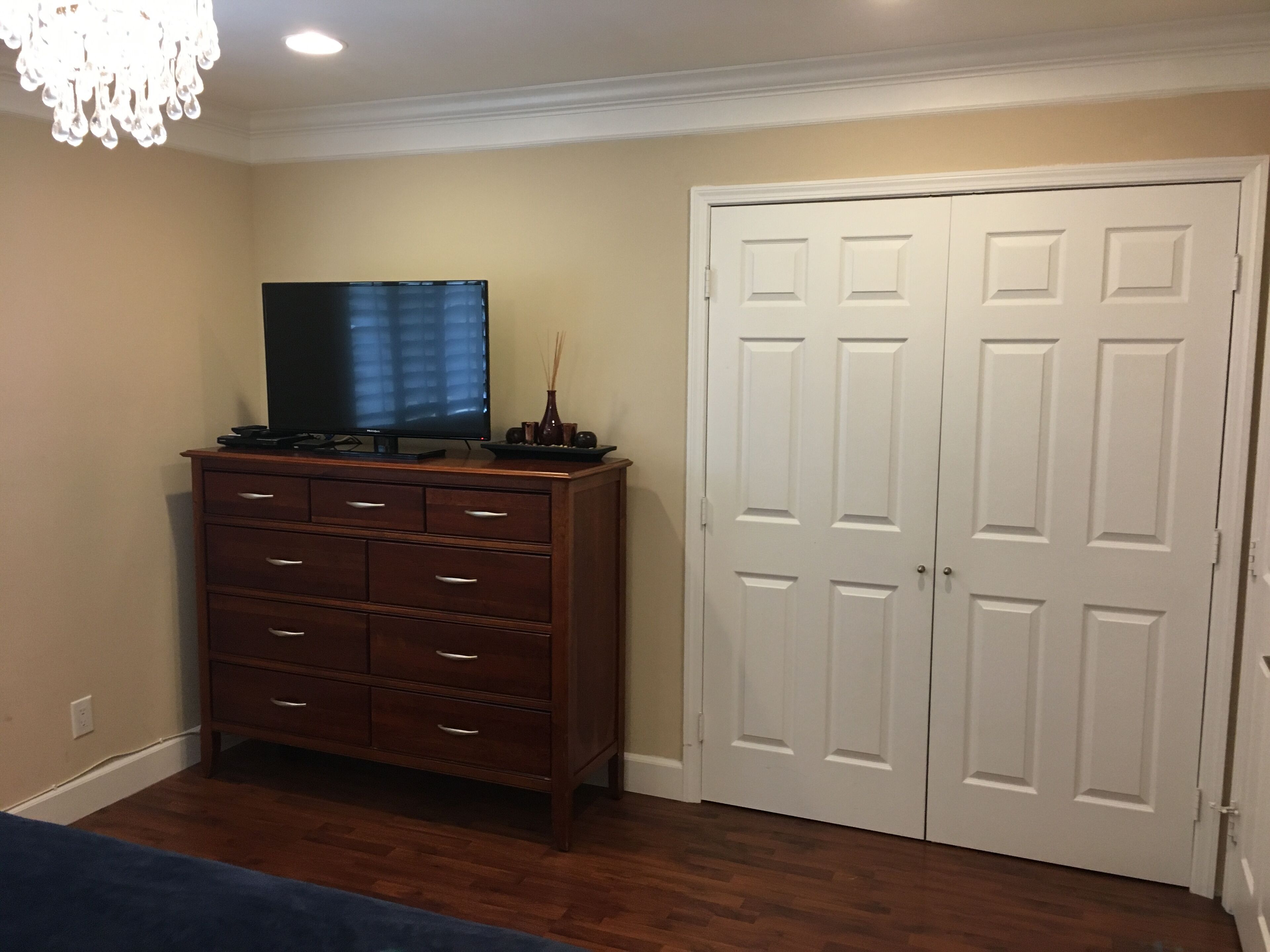 Una habitación con un aparador de madera, un televisor de pantalla plana y una puerta doble blanca.