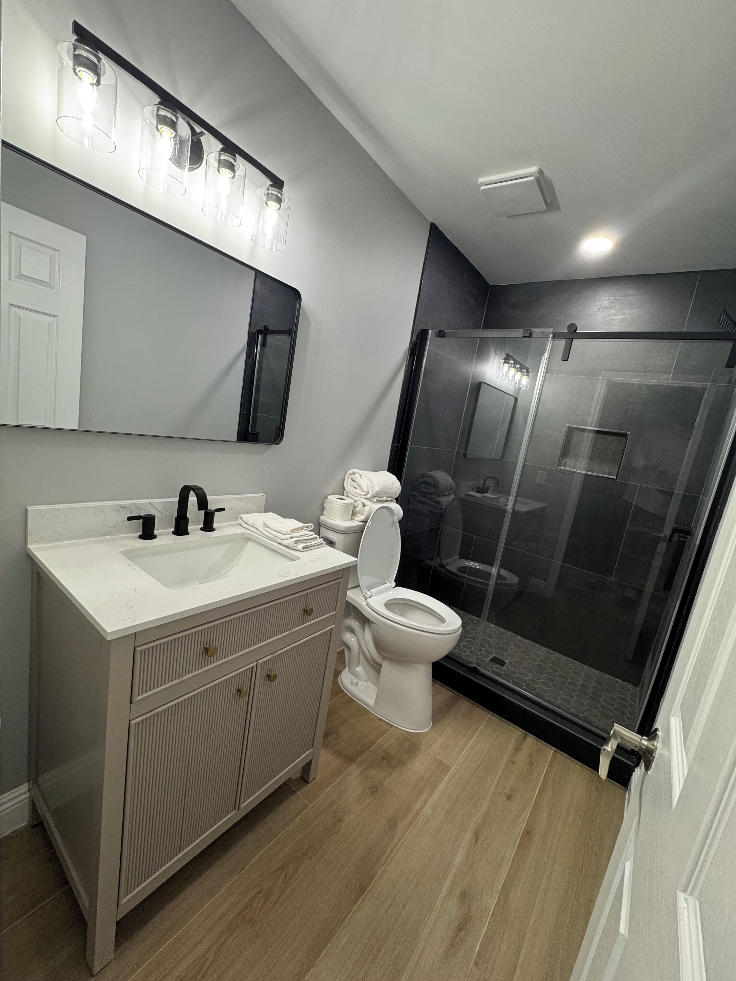 A modern bathroom with a white sink, a toilet, and a glass shower enclosure.