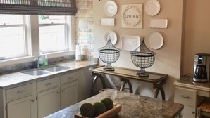 A kitchen with a marble countertop, a chandelier, and various decorative plates on the wall.
