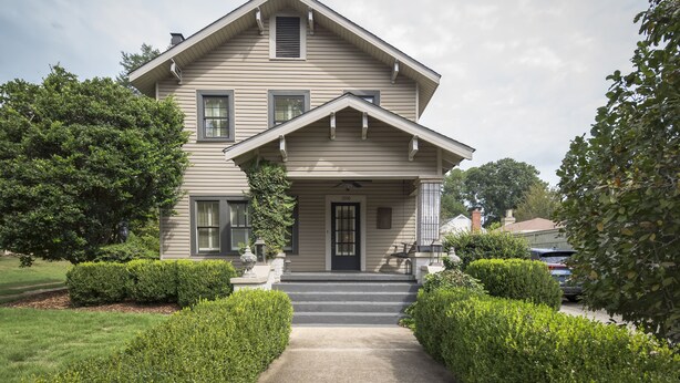 A two-story house with a front porch, a black door, and a number "2006" on the front.