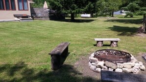 Ein Garten mit Feuerstelle, Bank und Picknicktisch.
