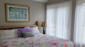 Ein Schlafzimmer mit einem Bett, einem Deckenventilator, einem gerahmten Bild und transparenten Vorhängen.