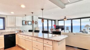 Una cucina moderna con una grande isola, mobili bianchi e vista sull'oceano.