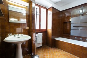 A bathroom with a pedestal sink, a bathtub, and a shower.