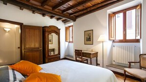 Una camera da letto con un letto grande, mobili in legno, una scrivania e una finestra con persiane.
