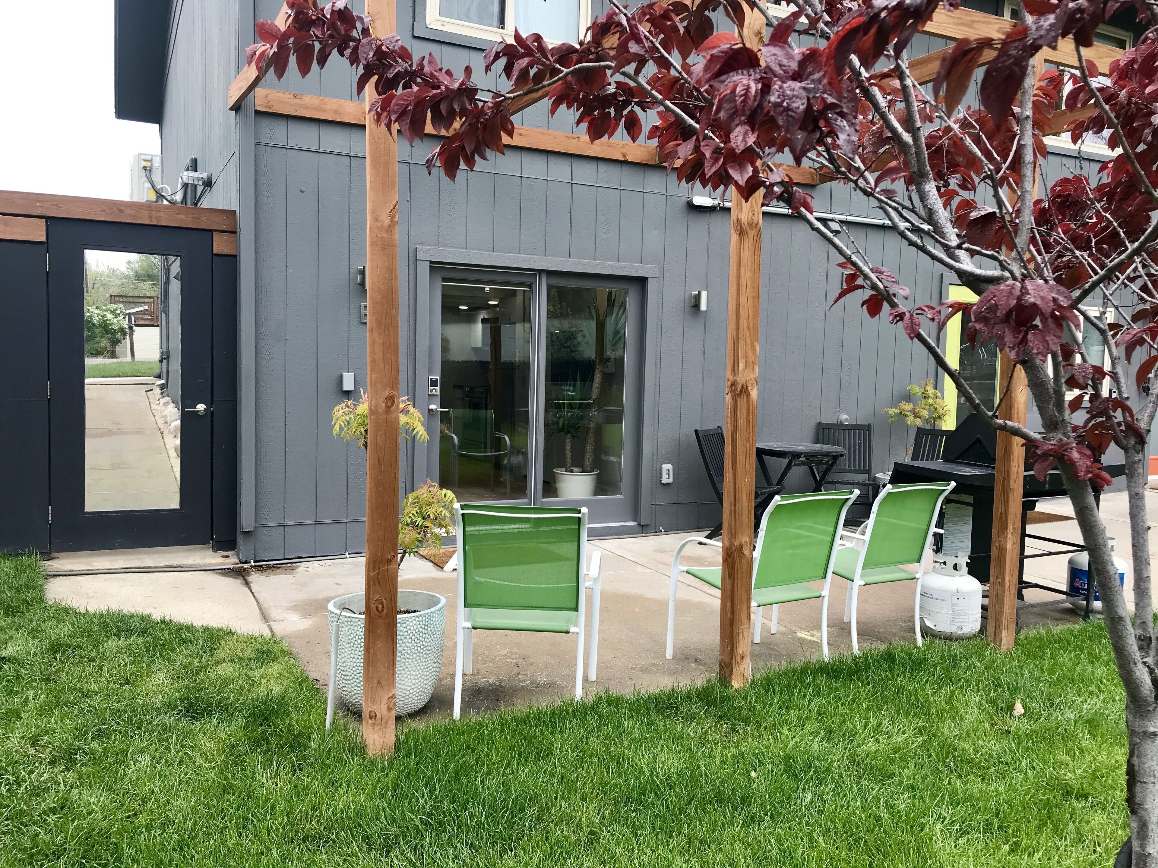 Un espace extérieur aménagé en terrasse, avec des sièges et l’entrée du bâtiment.