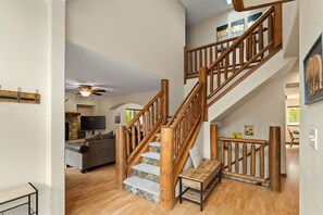 Staircase leads to a cozy seating area with a sofa and mounted TV.