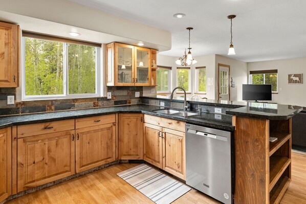 Enjoy cooking in this well-equipped kitchen with a granite countertop, wooden cabinetry, and island.