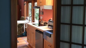 Une cuisine étroite avec des meubles en bois, un lave-vaisselle encastré et une fenêtre donnant sur un jardin.