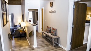 A hallway with a wooden bench, a coat rack, and a door leading to another room.