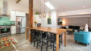A modern kitchen with a wooden dining table, black chairs, and a hanging light fixture. - Frontside Hacienda downtown Salida. STR #012962 (Salida)