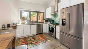 A modern kitchen with stainless steel appliances, a window, and a colorful rug. - Frontside Hacienda downtown Salida. STR #012962 (Salida)