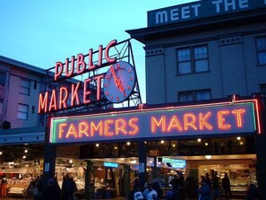 A public market with a clock and neon signs.