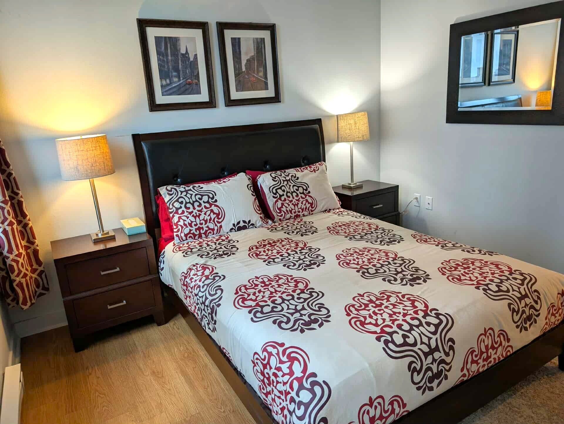 A neatly arranged hotel room with a large bed, two bedside tables, and a mirror on the wall.