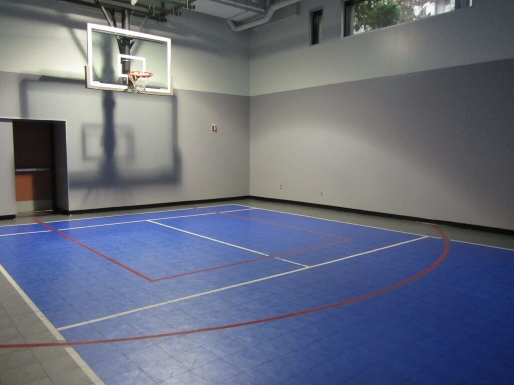 Un terrain de basket-ball intérieur avec un sol bleu et un panier de basket.