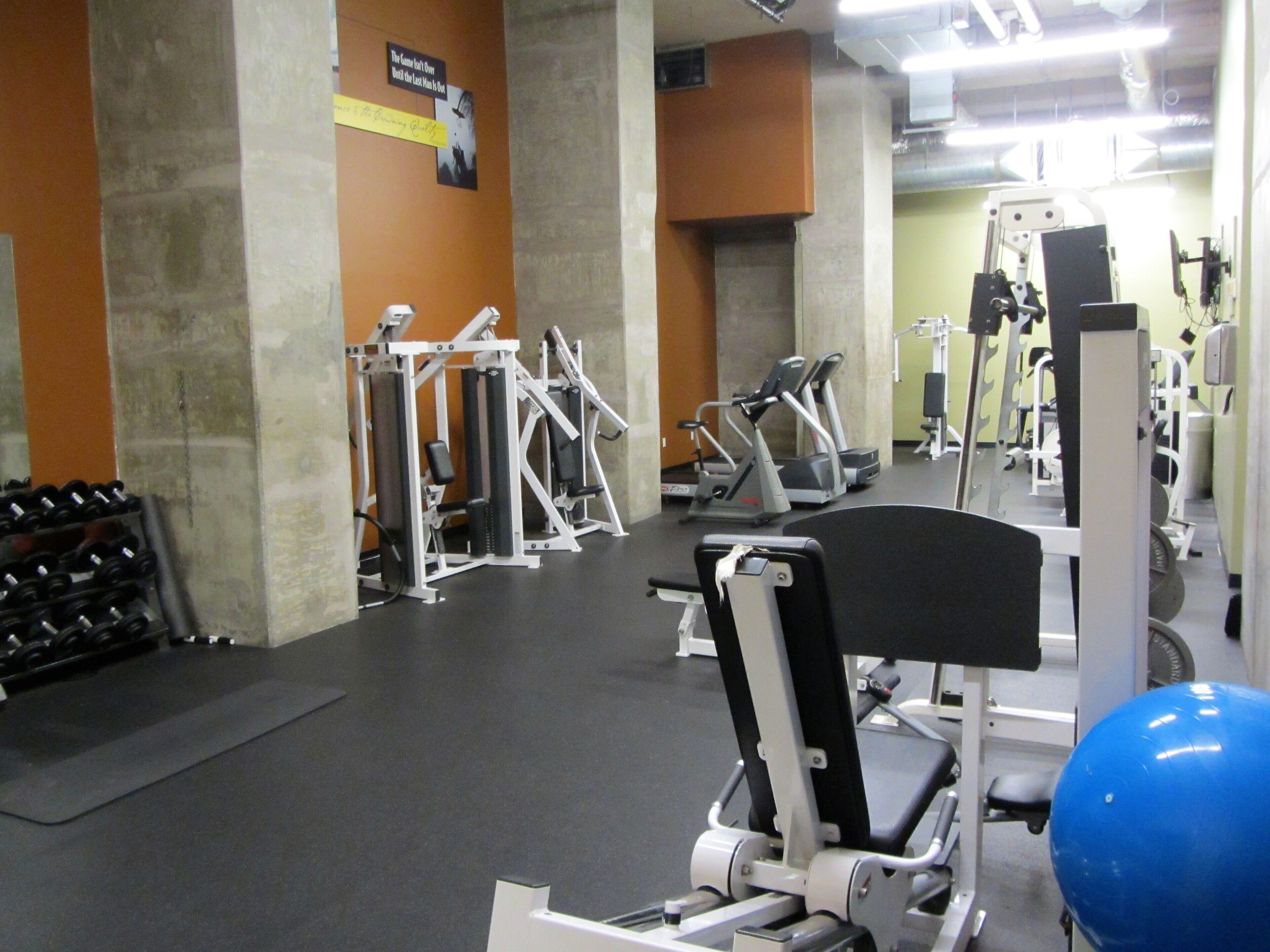 Une salle de sport équipée de divers appareils d’exercice, notamment des appareils de musculation et des appareils de cardio.