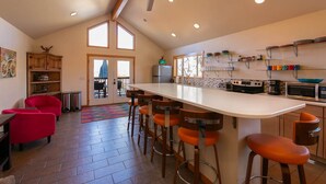A kitchen with a central island, bar stools, a ceiling fan, and a view through a glass door.