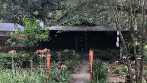 A garden pathway leading to a building with a dark roof, surrounded by various plants and flowers. - A SLICE OF "OLD FLORIDA" AMONG GRANDFATHER OAKS. (Crystal River)