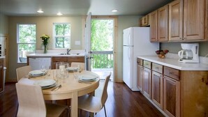 A kitchen with wooden cabinets, a dining table set for four, and a refrigerator.