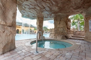 Relax by the tranquil pool surrounded by natural rock formations and a hot tub.