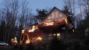 A two-story house with a balcony decorated with lights, surrounded by trees. - Reduced 50%on30+daysBchMTN/2BR/2BthNew/Clean/Comfort/sleeps4/Wifi/Cable/2mi2rsrt (Beech Mountain)