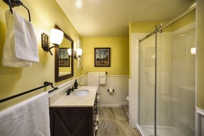 A bathroom with a sink, mirror, towel rack, and a glass shower enclosure. - Peachland Treehouse Suite (Peachland)