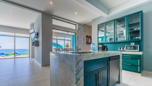 A modern kitchen with a marble island, built-in appliances, and teal cabinetry. - Casa Flor de Mayo  5BR Villa with Infinity Pool & Stunning Ocean Views (Isla Mujeres)