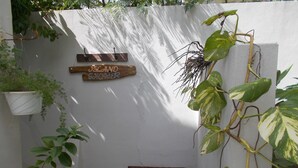 A small outdoor area with a wooden bench, a hanging plant, and a sign that reads "ISLAND SHOWER". - Dos Palmas-3Bdrm, 2Ba, Walk One Block to Caribbean,Malecon,restaurants,etc (Vieques)